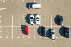 Aerial view of many colorful cars parked on parking lot with lines and markings for parking places